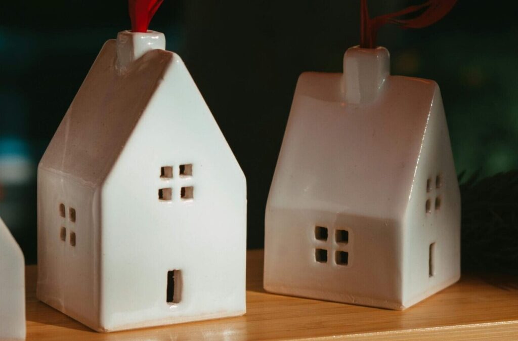 Charming ceramic house ornaments with ribbon loops on display, perfect for festive decor.